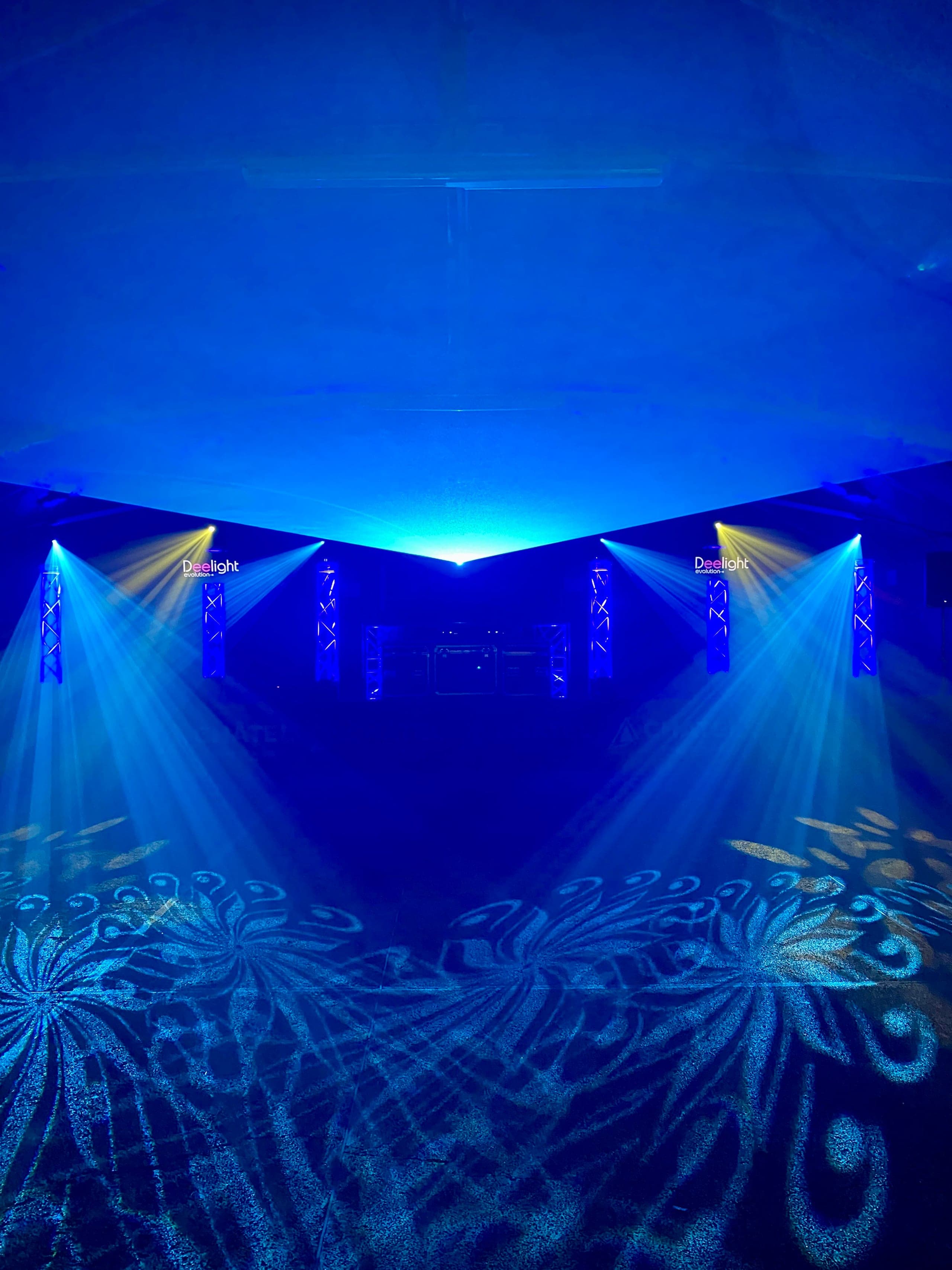 Installation lumière Deelight Evolution pour un mariage en Haute-Savoie : colonnes de structure, faisceaux bleus et projections florales sur la piste de danse